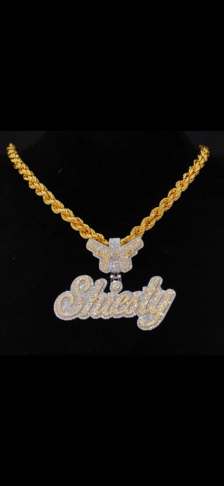 Gold rope chain with an iced-out butterfly bail and pavé-set nameplate pendant on a black background